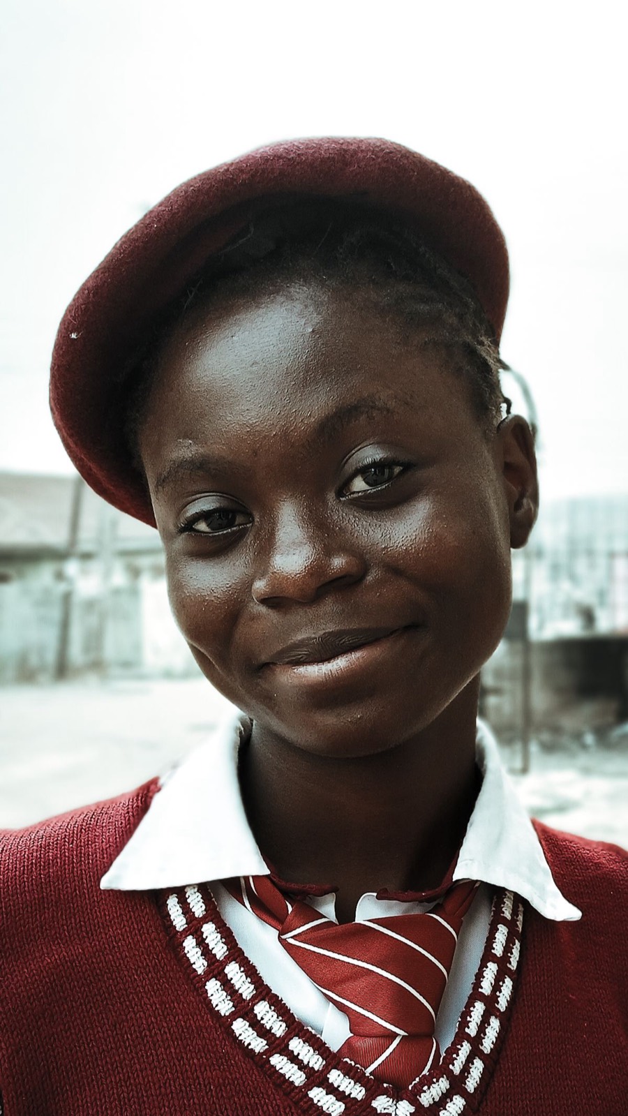 A smiling Ghanaian schoolgirl in her school uniform
