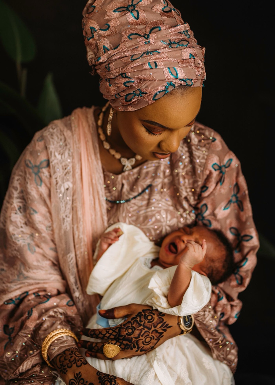 A mother tenderly holding her swaddled newborn baby